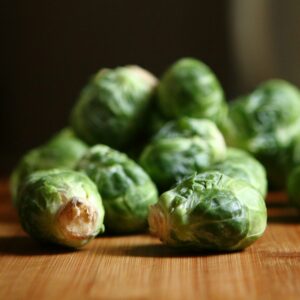 Firm green Brussels sprouts on a wooden chopping board.